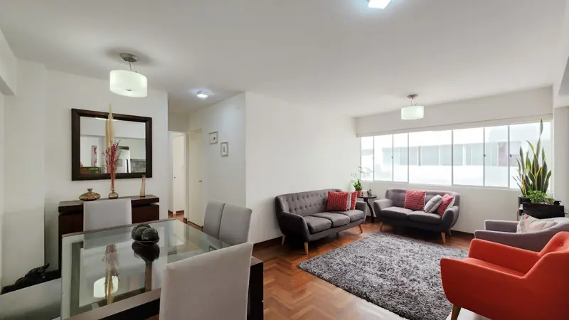 Sala y comedor con piso de parquet, sofás y ventana amplia